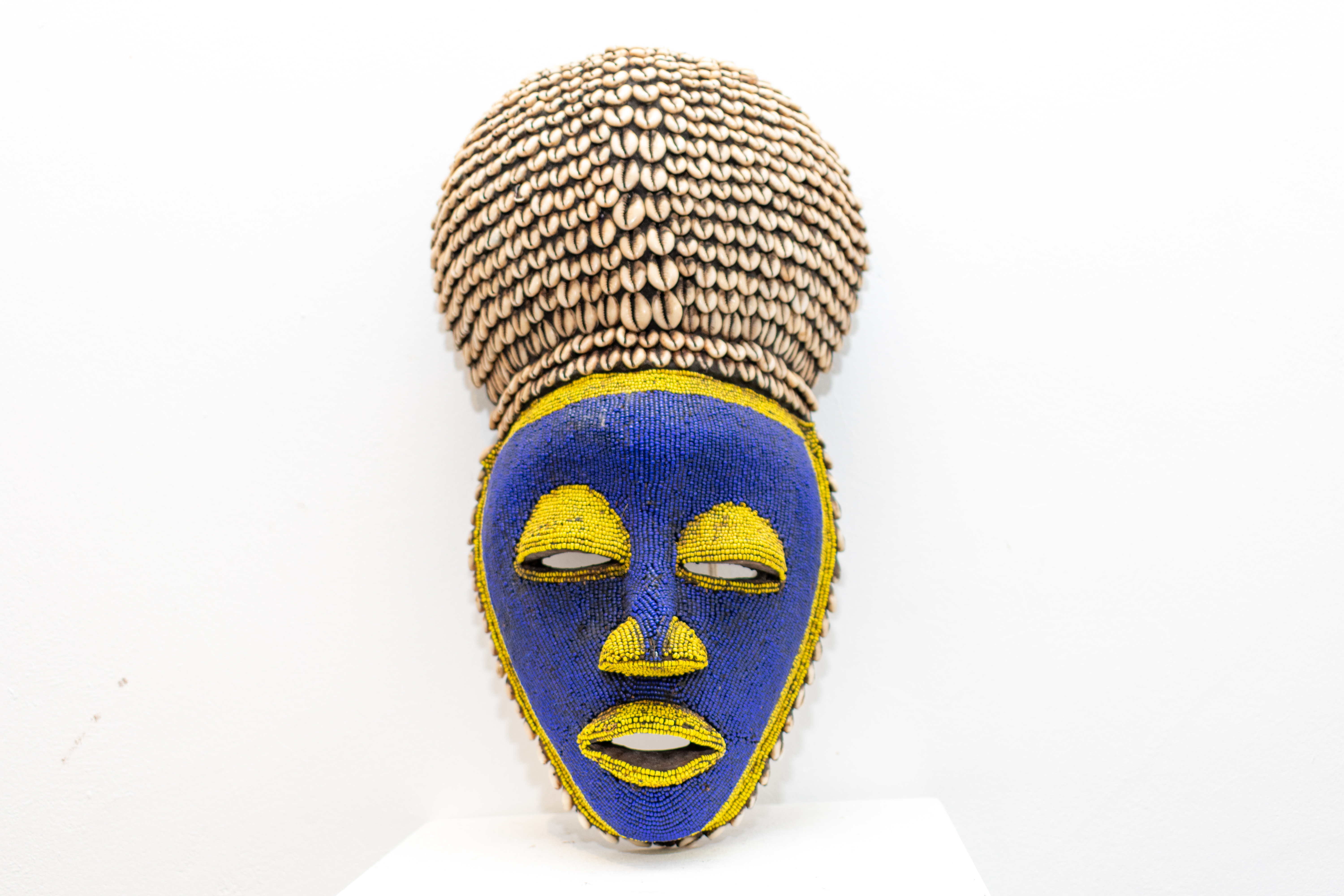 Blue and yellow beaded African mask with a cowrie-shell headdress representing the Tribal Gallery